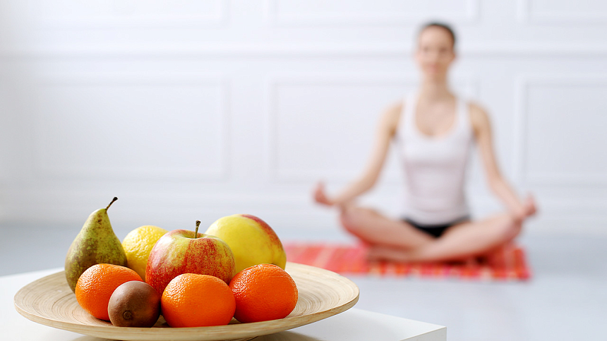 fruits on a plate with a girl practicing yoga in the background